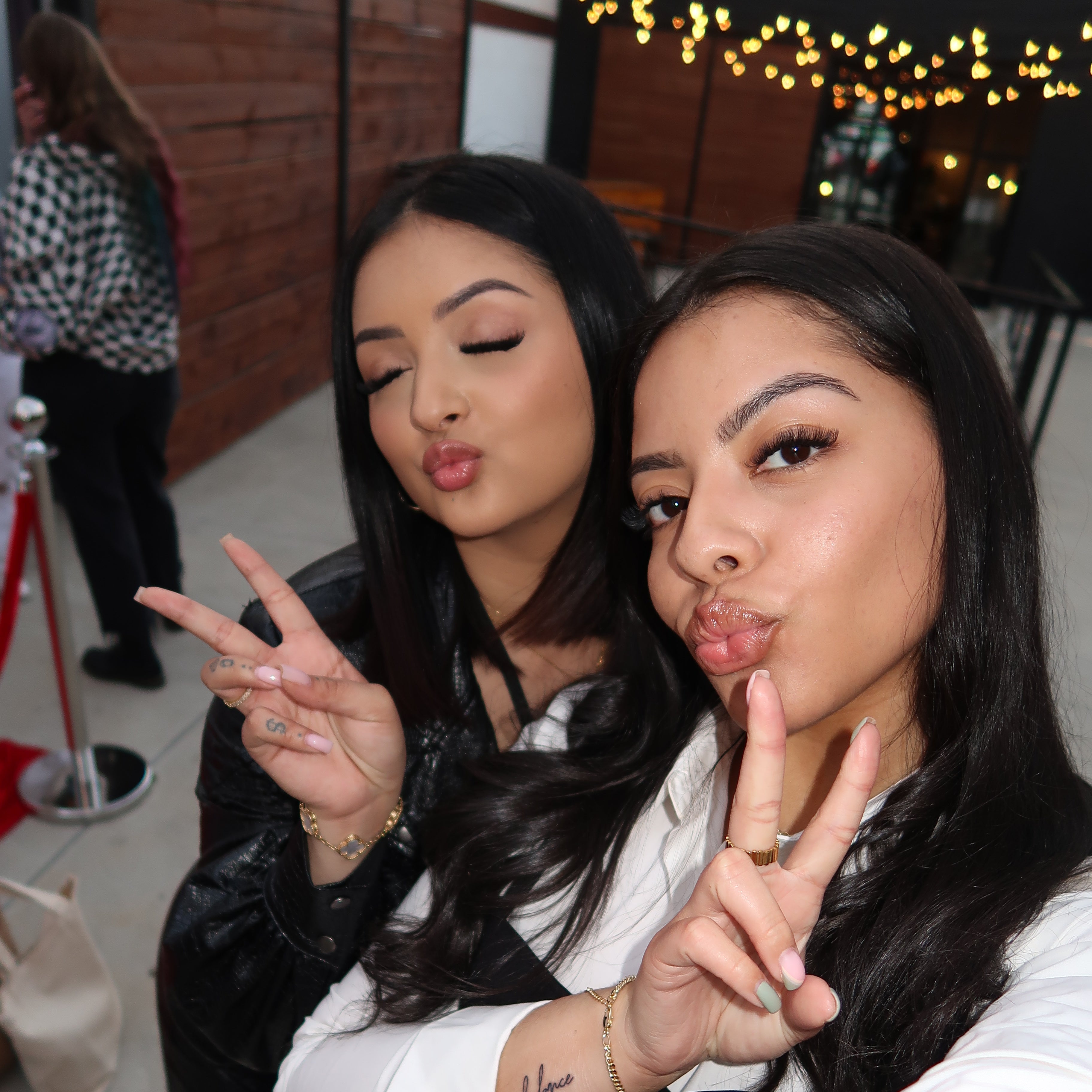 Two women posing for a photo with one making a peace sign, lights in the background. Lash Social Convention in Atlanta Georgia